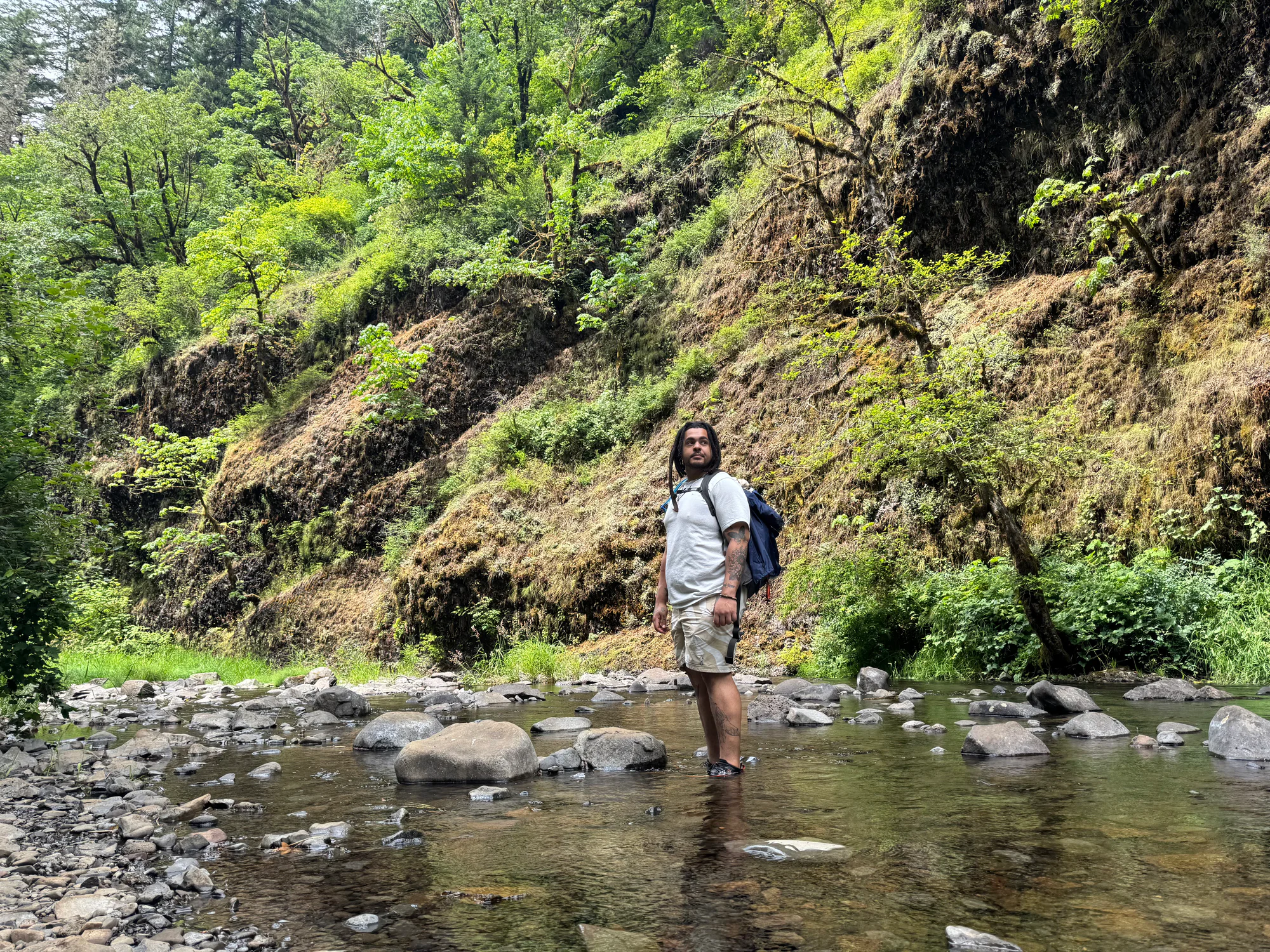 Jonathan standing in a forest riverbed beneath a green canyon.