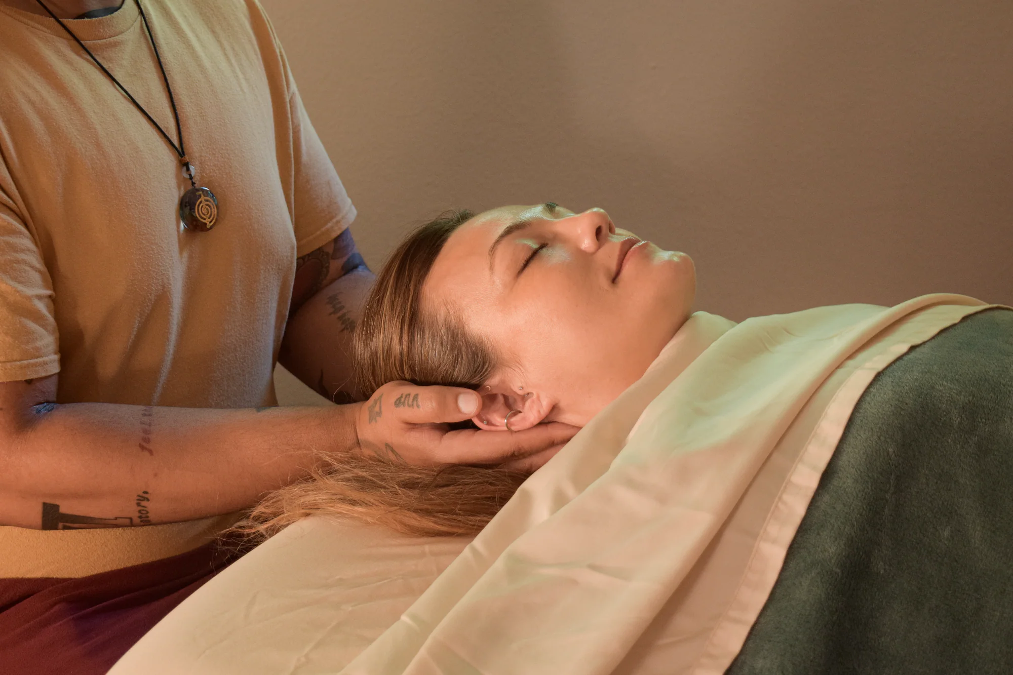 Jonathan providing attentive, grounded massage while a client rests beneath secure draping.